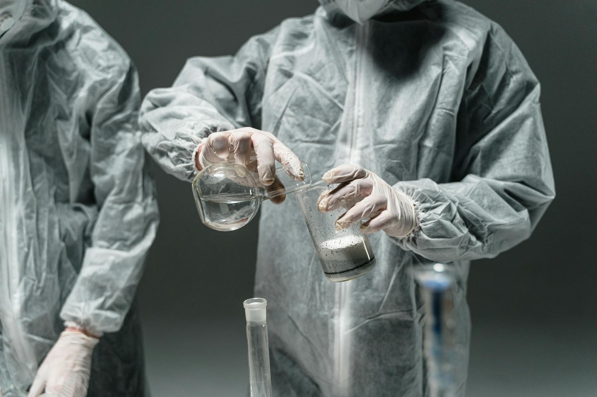 Researchers in protective suits working with beakers in a science lab.